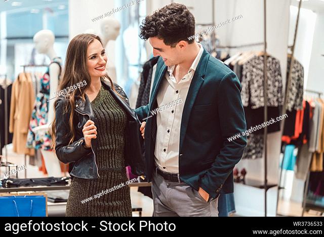 Woman showing her man new leather jacket in store or fashion boutique