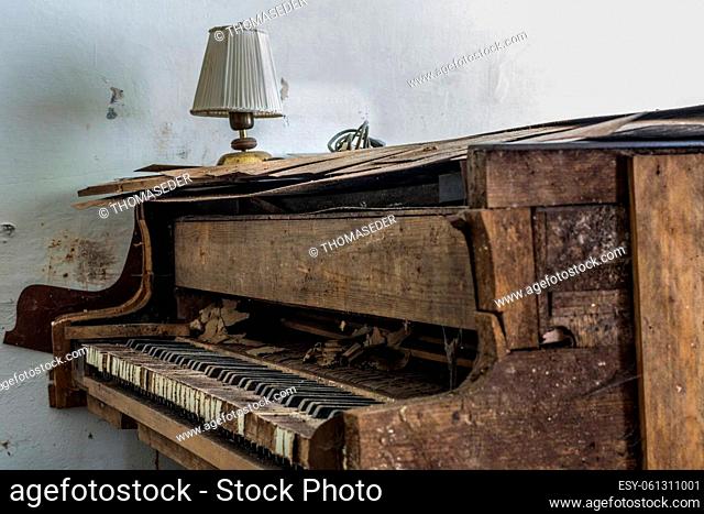 broken old piano and a lamp in a abandoned house