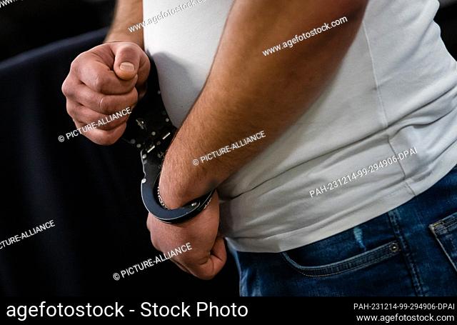 14 December 2023, Baden-Württemberg, Stuttgart: One of five defendants stands handcuffed in a courtroom of the district court