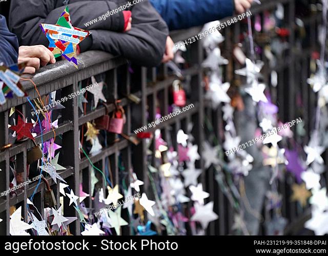 19 December 2023, Hamburg: Homemade stars on yogurt and pudding lids hang from the Michaelis Bridge. In the world record attempt