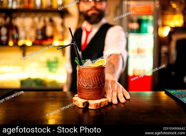 Barkeeper shows attractive alcoholic cocktail. Handsome alcohol beverage preparation