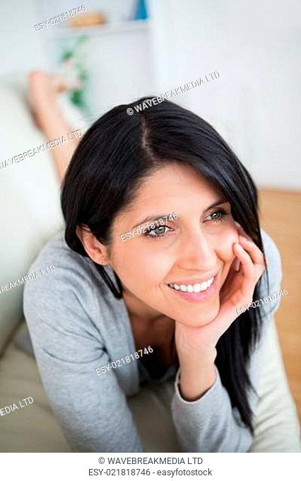 Woman smiling as she holds her head with her fist on a couch in a living room