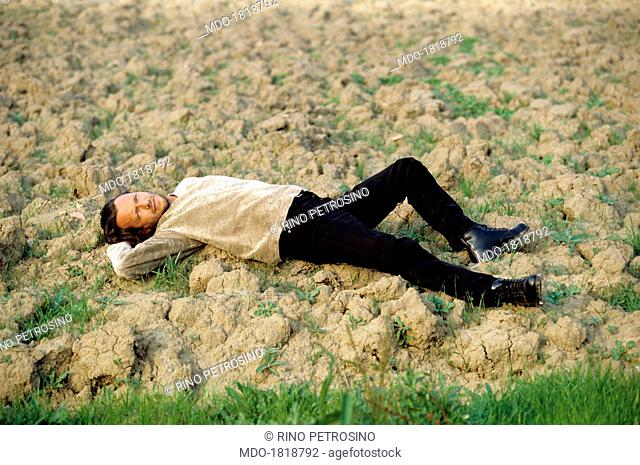 Italian singer-songwriter Biagio Antonacci lying on the bleak grass. 1996