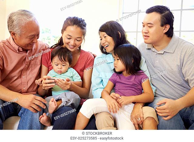 Multi Generation Family Sitting On Sofa With Mobile Phone