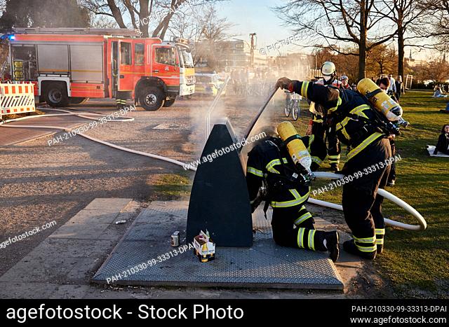 30 March 2021, Hamburg: Firefighters extinguish a smoking large waste container on the Alsterwiese Schwanenwik. Photo: Georg Wendt/dpa