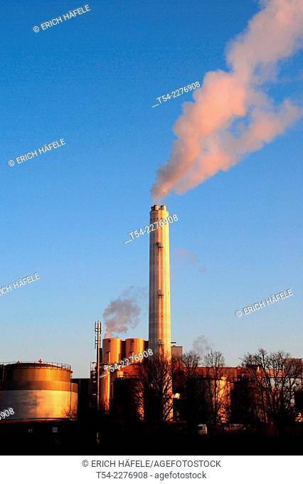 Smoke rises from the chimney of a factory