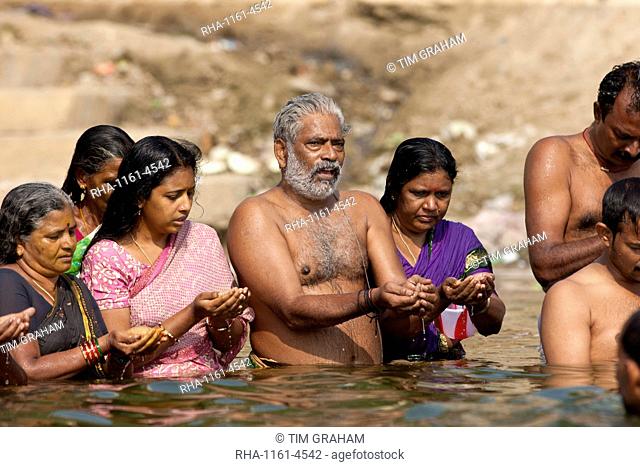Indian Hindu men and women bathing and praying in the River Ganges by Kshameshwar Ghat in holy city of Varanasi, India
