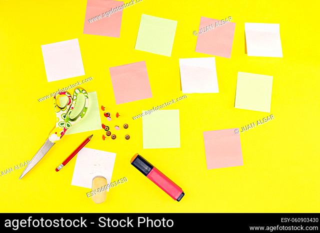 Studio photo with yellow background with stationery as post-its, pencil, scissors, eraser and marker
