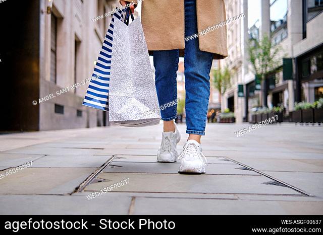 Woman with shopping bags walking on footpath