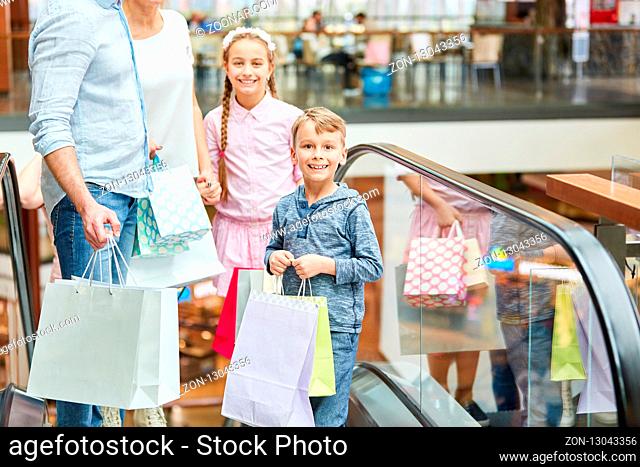 Familie und Kinder mit vielen Einkaufstüten auf der Rolltreppe im Einkaufszentrum