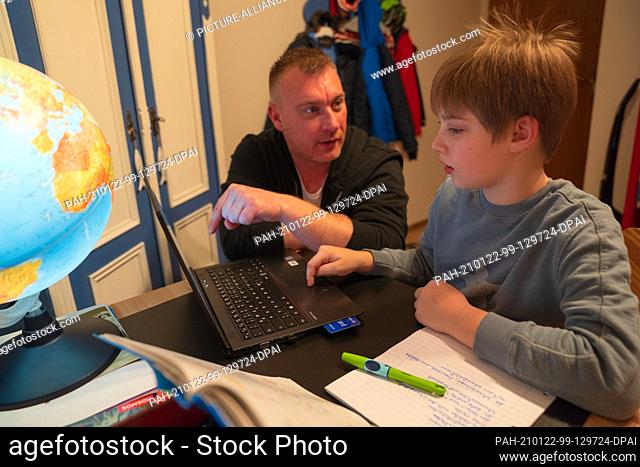 ILLUSTRATION - 16 January 2021, Bavaria, Neustadt Bei Coburg: A boy uses a laptop with his father for homeschooling. Photo: Nicolas Armer/dpa
