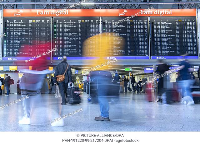 20 December 2019, Hessen, Frankfurt/Main: Passengers walk past the display board in Terminal 1 of the airport. An increase in passenger numbers is expected in...