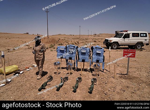 18 May 2022, Iraq, Tal al-Reem: A female member of the Swiss Foundation for Mine Action (FSD) stand next blast suits and mine detectors at the village of Tal...