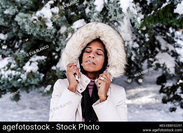 Mature woman with eyes closed in park during winter