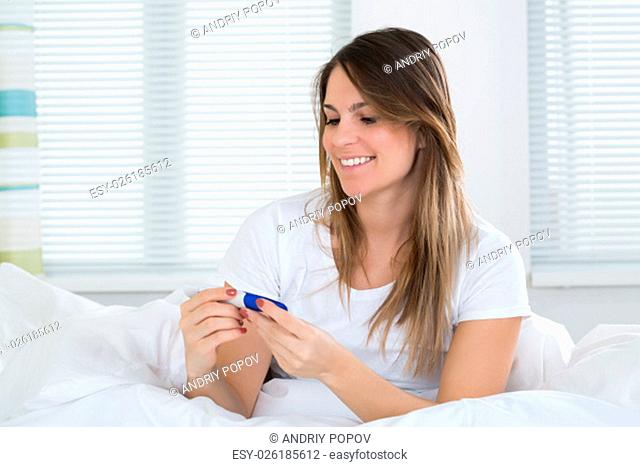 Young Happy Woman Looking At Pregnancy Test Kit