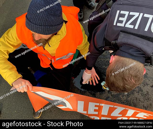 17 March 2023, Cologne: A climate activist sits on a street in Cologne. Activists from the climate group Last Generation got stuck on a major traffic artery in...