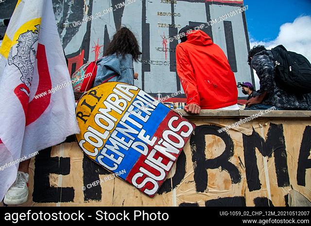 A demonstrator holds a sign with the shape of a grave and the Colombian flag that reads ""R.I.P Colombia is a Cementrery of Dreams"" as Bogota