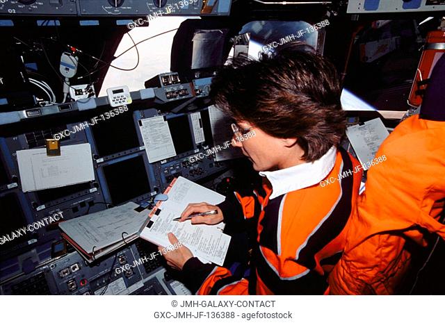 Astronaut Nancy J. Currie, STS-109 mission specialist, looks over a procedures check list while occupying the pilot's station on the forward flight deck of the...