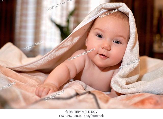 Sweet small baby with towel lies on the bed at home