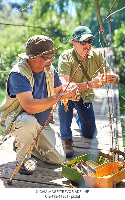 Active senior male friends preparing fishing lines