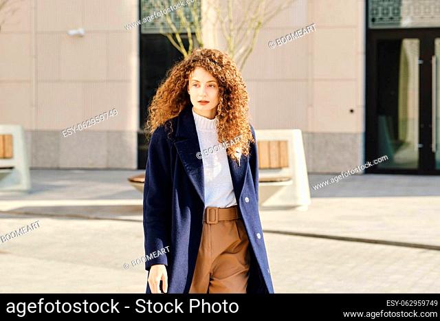 Young woman walking along the street among modern buildings