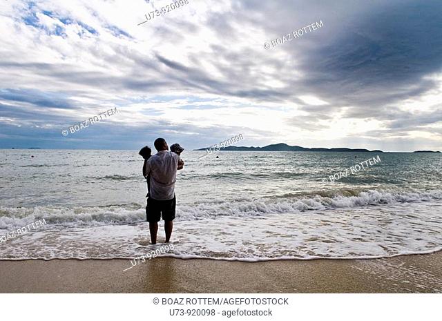 Father and his twins enjoy the sunset on a tropical beach
