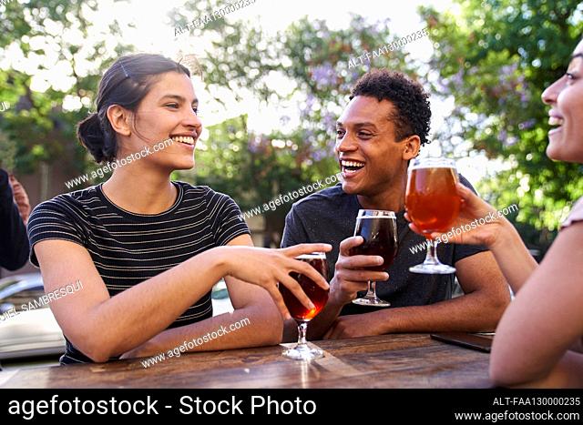 Mid-shot of young Latin-American woman and her diverse group of friends enjoying craft beer