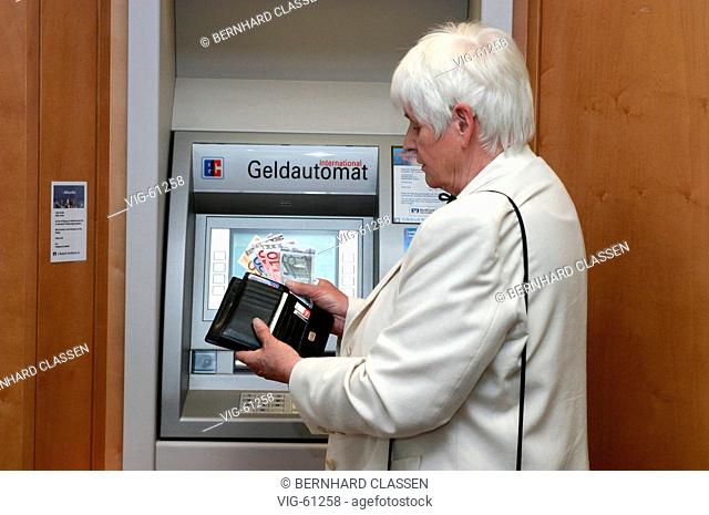 Old age pensioner drawing Euro bank notes from a cash machine ( posed ). - WINSEN, GERMANY, 20/05/2004
