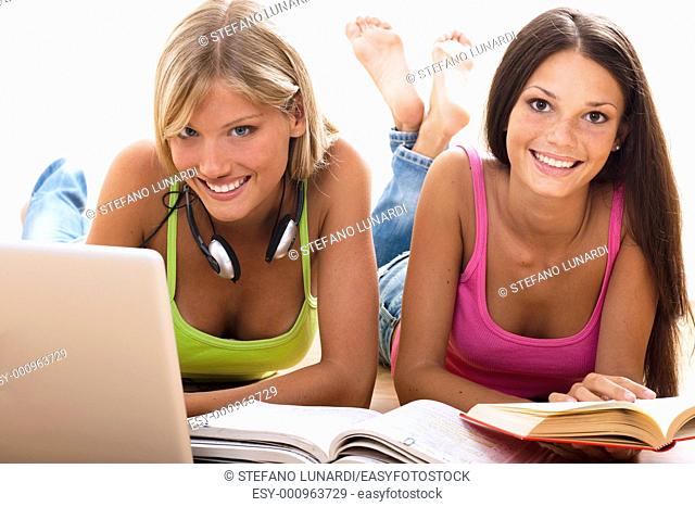Happy teenage girls studying on the floor