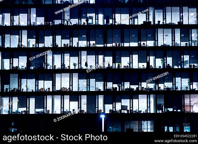 Office Building At Night. Late night at work. Glass curtain wall office building. Office building exterior in the late evening with interior lights on