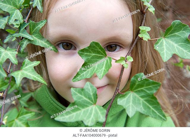 Little girl looking through ivy, close-up
