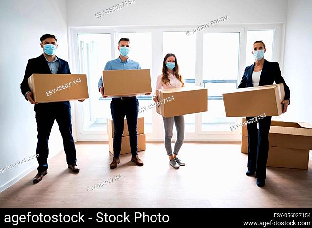Office Relocation. Executives Moving Cardboard Boxes In Face Masks