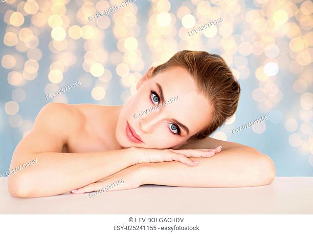 beauty, people, holidays and bodycare concept - beautiful young woman face and hands over lights background