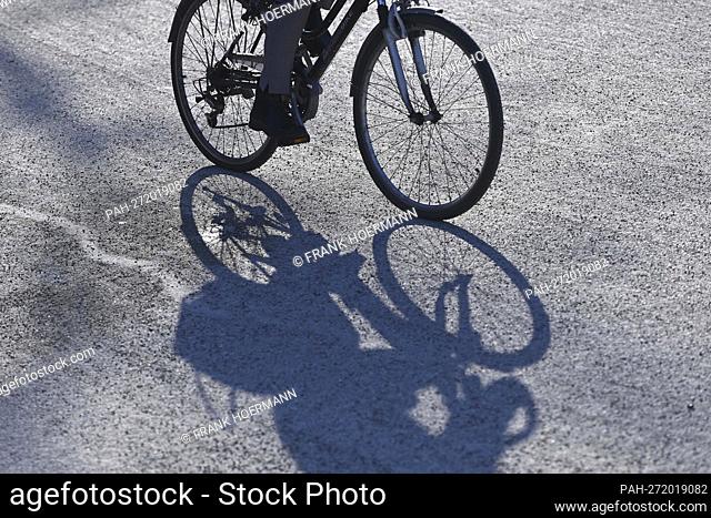 Cyclist, cyclist, woman, cyclist rides a bike through Munich and casts a long shadow. - Munich/Bayern/Deutschland