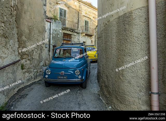 Tourists on a tour in old Fiats 500 through the narrow streets of Modica on the island of Sicily in Italy