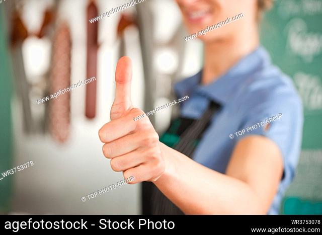 Closeup of female butcher showing thumbs up sign