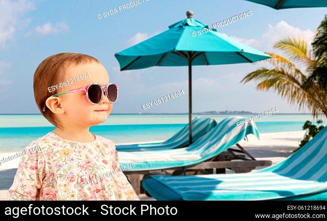 happy baby girl in sunglasses on summer beach