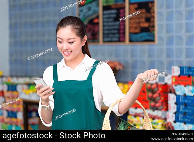 young pretty chinese woman works in fruit store