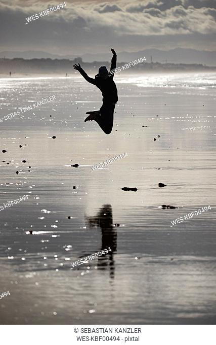 Female jogger jumping at the beach