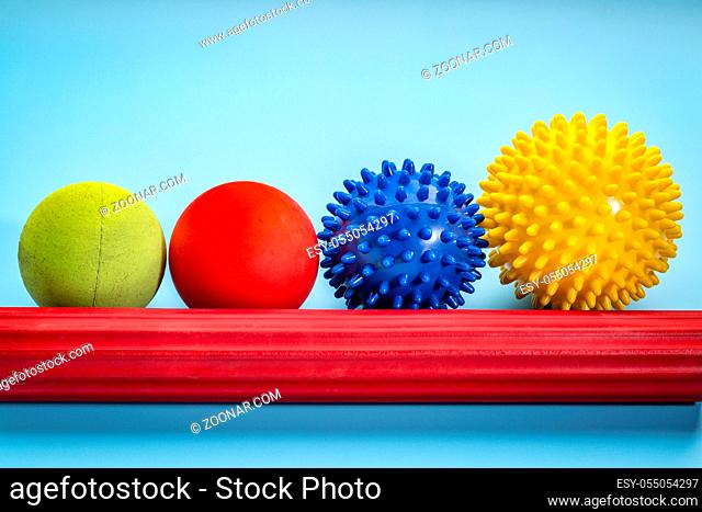 self massage and reflexology therapy concept - a set of small rubber balls and roller bar against blue background