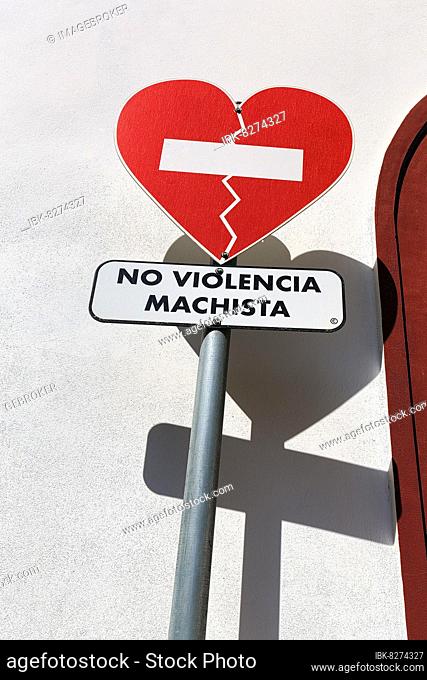 Rotes Verkehrsschild wirft Schatten auf weiße Wand, gebrochenes Herz, Aufschrift No Violencia Machista in einer Kampagne gegen häusliche Gewalt