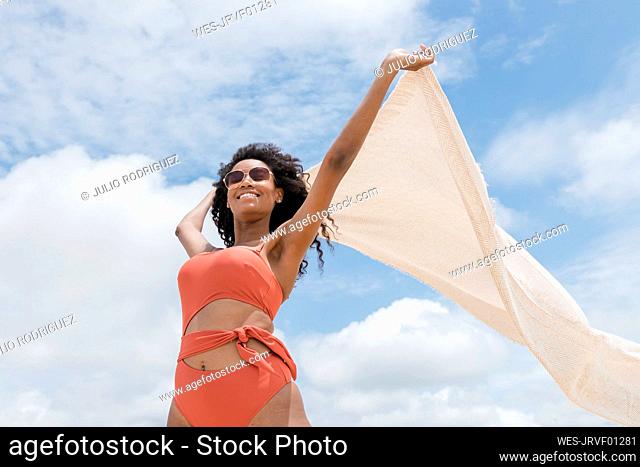 Young woman holding beach towel on sunny day