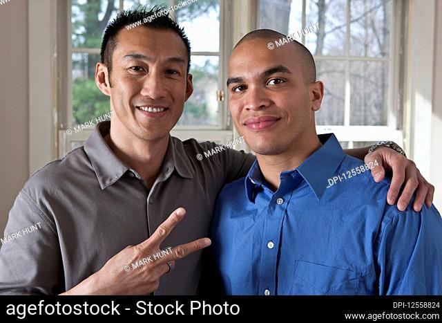 Portrait of two young businessmen standing side by side in an embrace with thumbs up