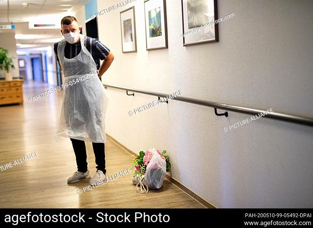 10 May 2020, North Rhine-Westphalia, Heinsberg: Lars Dressen (r) puts on a disposable apron before visiting his grandmother in the Johannes Sondermann House of...