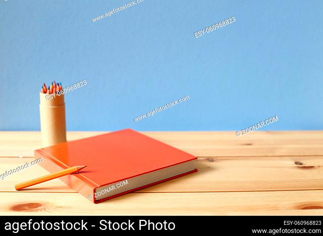Notebook and colored pencil on wooden desk