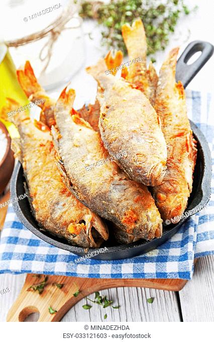 Fried fish in a frying pan on the table