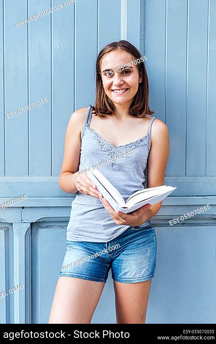 Young girl smiles and holds a bluish gray open white paper