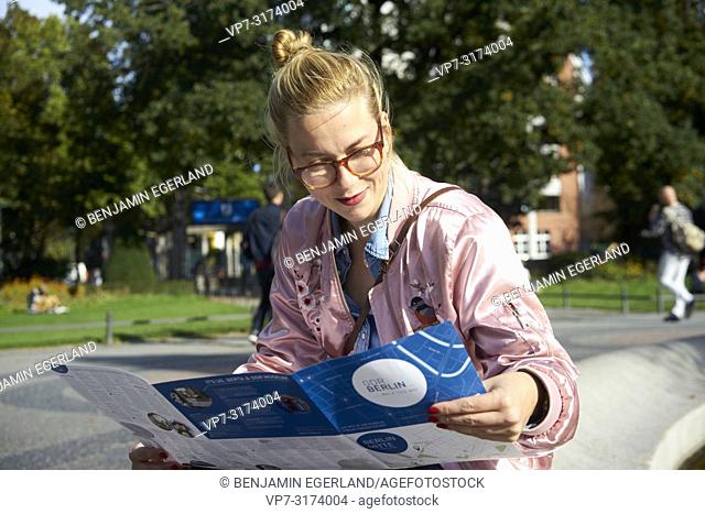 Woman reading city guide map, in Berlin, Germany