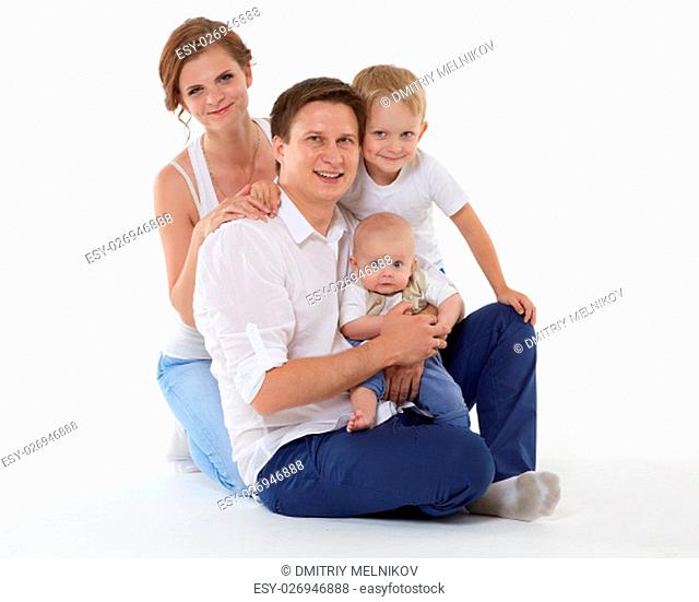 Young parents with sweet children sit on a white background. Happy family. Six month and four years