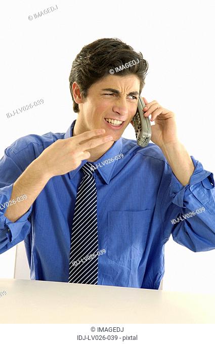 Businessman talking on a cordless phone and making a gun sign